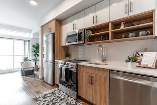A modern kitchen with wooden cabinets and stainless steel appliances.at Podium Apartments, Calgary, AB