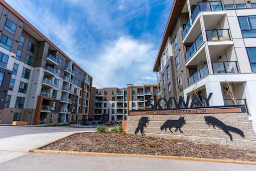 The image shows a modern apartment complex named Skyway with a sign featuring three wolves.