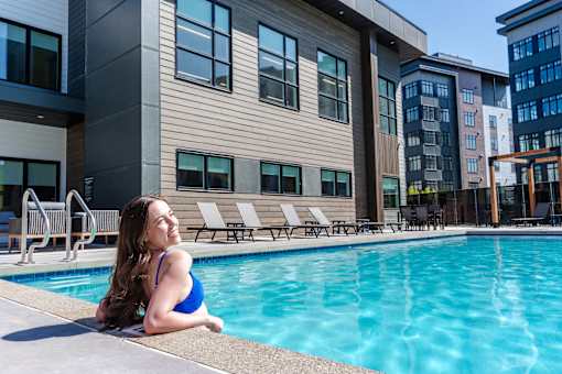 A Woman In a Blue Bikini Sits By a Pool at Podium Apartments, Alberta, T2E 7J2