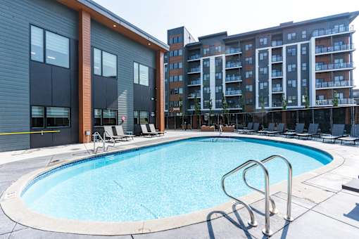 A swimming pool with a metal ladder in front of a building.