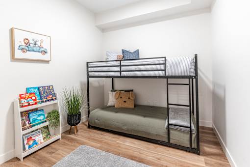 A room with a bunk bed, a bookshelf, and a plant.at The Artisan at Rangeview, Calgary, Alberta