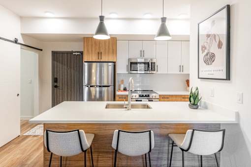 A modern kitchen with a white island and grey chairs.at The Artisan at Rangeview, Calgary, Alberta