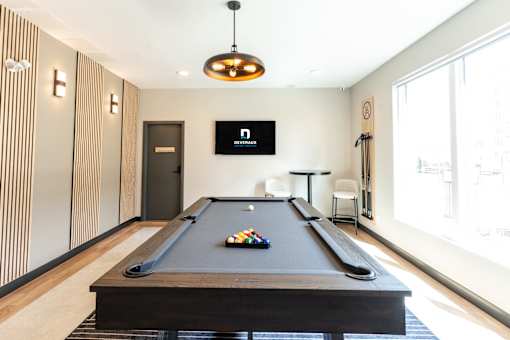 A pool table in a room with a TV mounted above it.