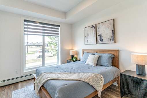 A bedroom with a bed, nightstand, and two framed pictures on the wall.