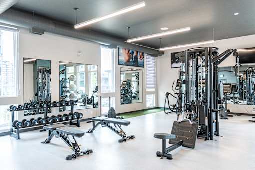 A gym with a variety of equipment including weights and benches.