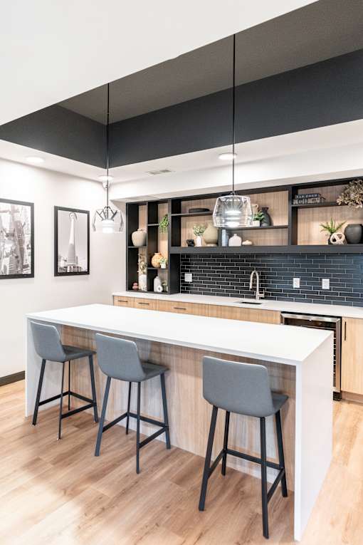 A kitchen with a white counter and two grey bar stools.