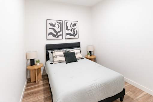 A bedroom with a large bed and two lamps.