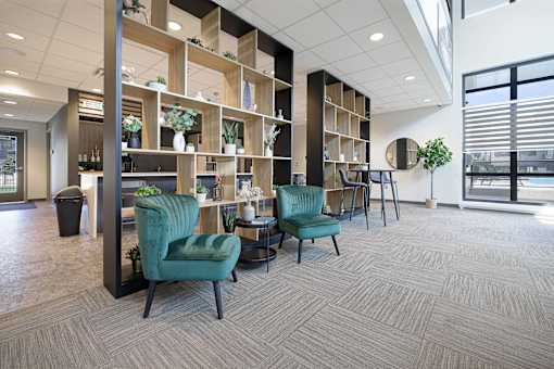 A room with a green chair and a wooden shelf.