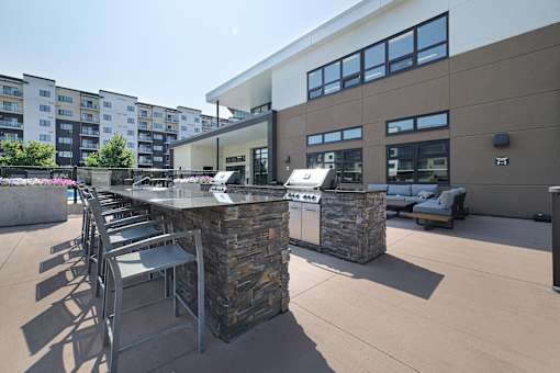 A modern outdoor seating area with a stone barrier and metal chairs.