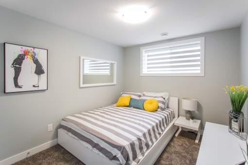 A bedroom with a bed, nightstand, and a painting on the wall.
