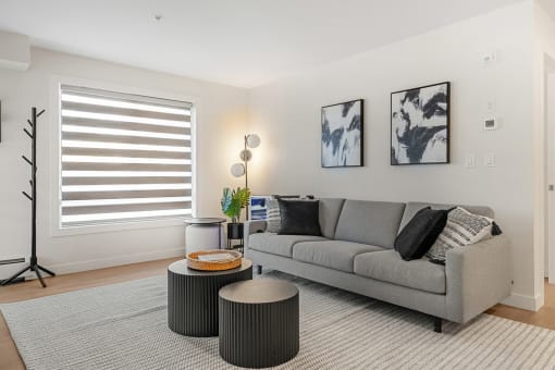 a living room with a gray couch and two round tables