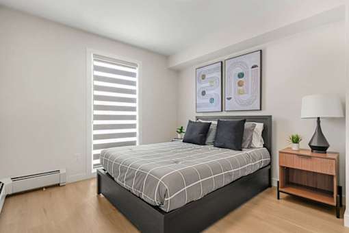 A bedroom with a large bed and a wooden nightstand.