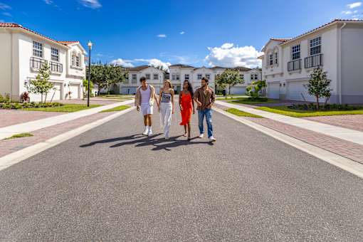 A group of people are walking down a street in a residential area at The Falls of Portofino , Naples, FL