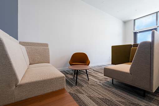 A room with a grey sofa, a brown chair and a grey chair.