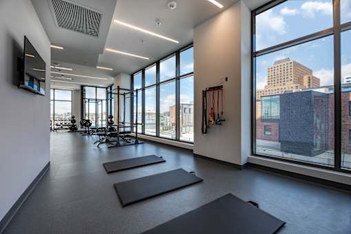 A yoga studio with mats on the floor and a view of the city outside the windows.