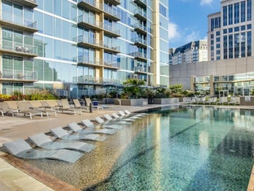 a large pool with lounge chairs in front of a tall building