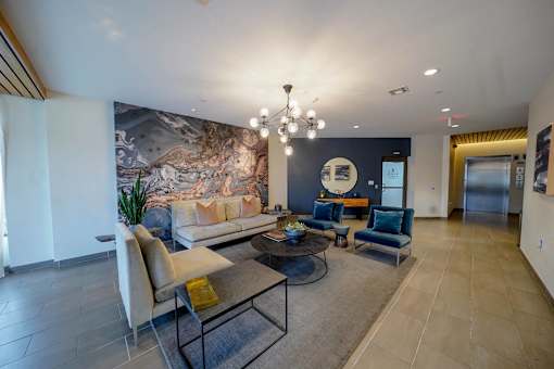 A living room with a large painting on the wall and a chandelier hanging from the ceiling.
