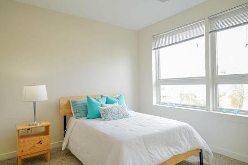 A bedroom with a bed, nightstand, and window.