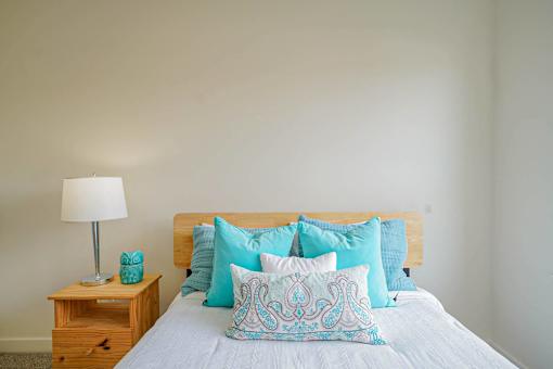 A bed with a white comforter and blue patterned pillow.