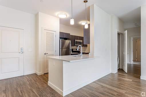 A kitchen with white cabinets and a wooden floor.