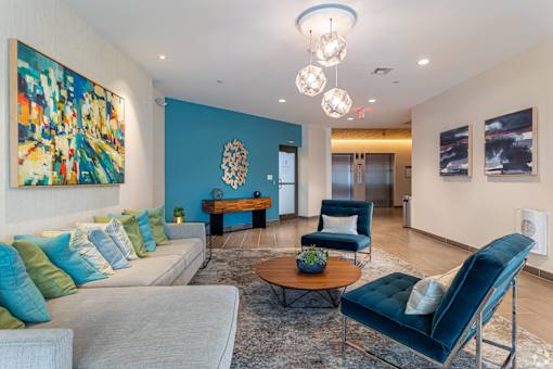 A living room with a grey couch, a blue chair, and a painting on the wall.
