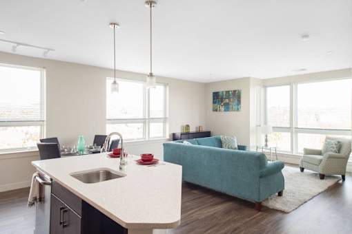 A kitchen with a blue couch and a painting on the wall.