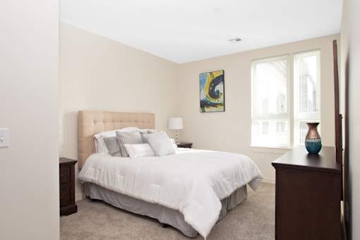 A bedroom with a large bed and a painting on the wall.