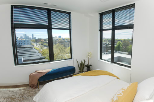 a bedroom with a bed and windows with a city view