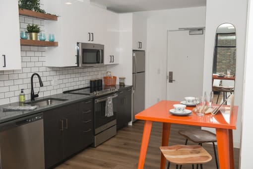 a kitchen with black appliances and an orange table