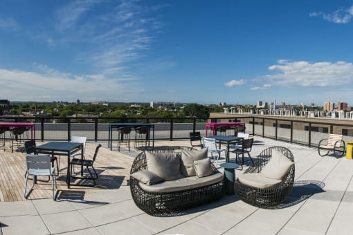 a rooftop patio with chairs and tables and a view of the city