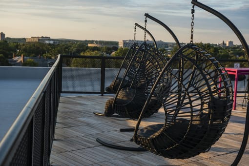 two swinging chairs on the roof of a building with a city in the background