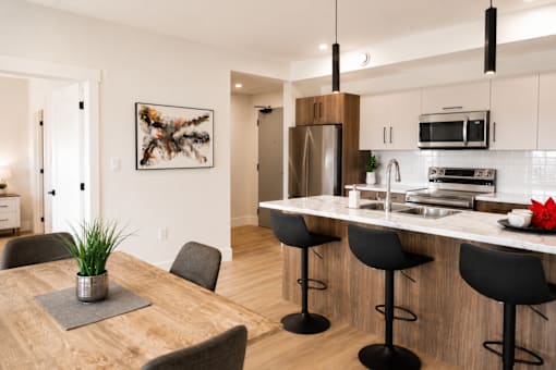 A modern kitchen with a wooden table and black bar stools.