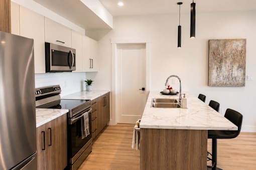 A modern kitchen with a marble countertop and stainless steel appliances.