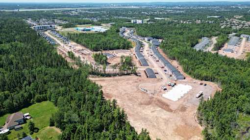 An aerial view of a construction site surrounded by trees and buildings.