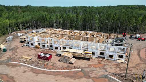 A large building under construction with a red truck parked in front.