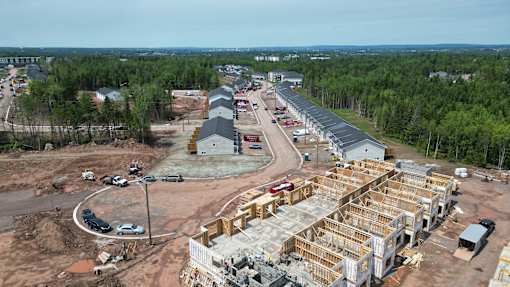 A construction site with a building under construction surrounded by trees.