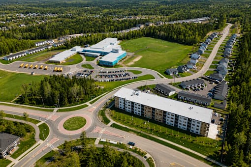 An aerial view of a roundabout with a building complex and a parking lot.