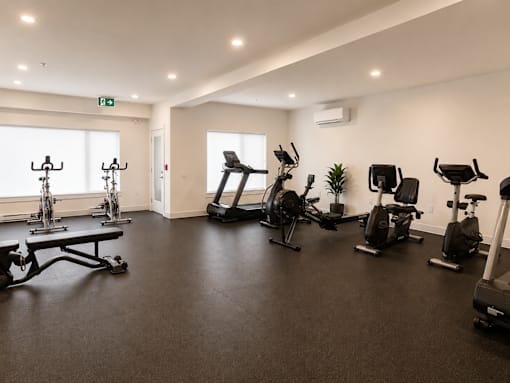 A gym with a variety of exercise equipment including treadmills, stationary bikes, and weight machines.