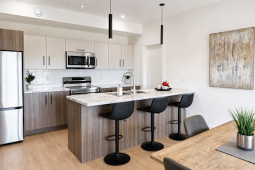 A modern kitchen with a wooden island and black barstools.