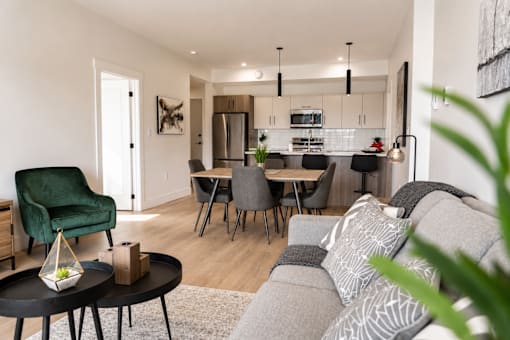 A modern living room with a green armchair and a grey sofa.