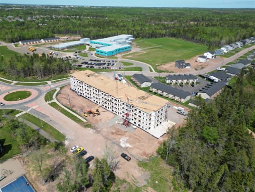 an aerial view of a building with a construction site and a parking lot