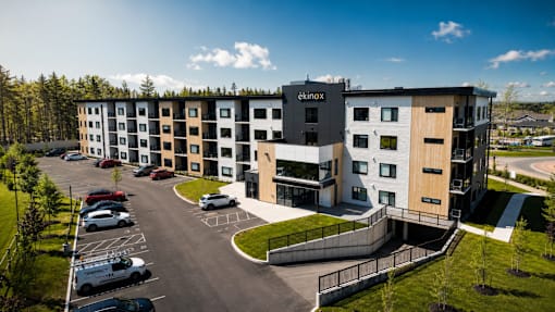 A modern apartment complex named "aknox" is surrounded by a parking lot and greenery.