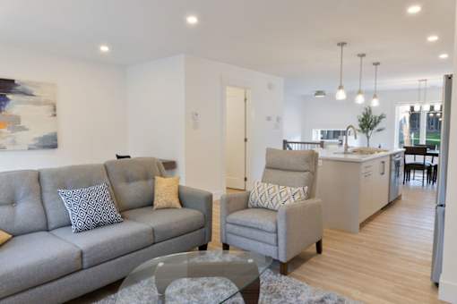 A grey couch with a grey and white pillow sits in a living room.