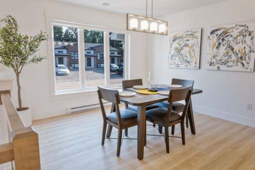 A dining room with a table set for two and a view of a parking lot outside.