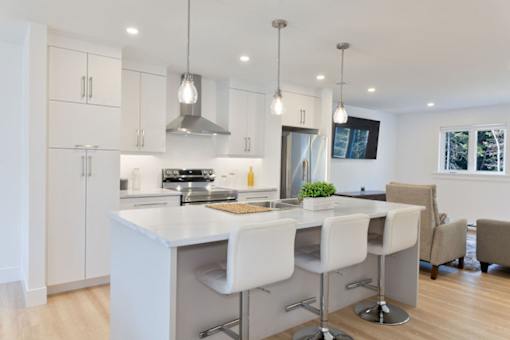 A modern kitchen with white chairs and a large island.