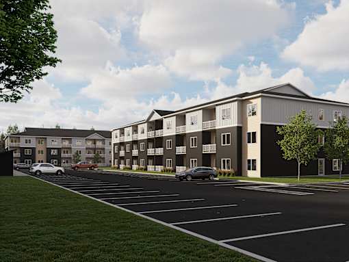 A modern apartment complex with a parking lot in front.