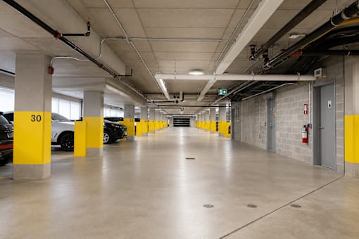 A parking garage with yellow poles and a fire extinguisher on the wall.