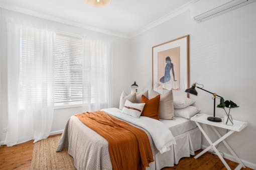 a bedroom with white walls and a bed with white and orange pillows