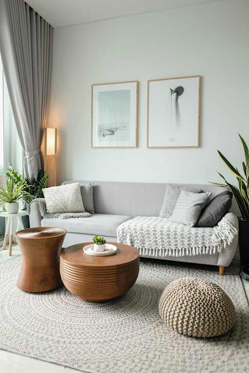 A living room with a grey couch, a wooden table, and two framed pictures on the wall.