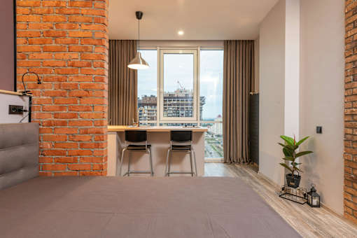A room with a brick wall and a grey carpet.